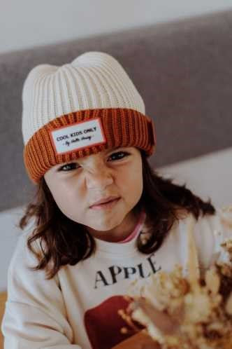 Menina com gorro creme e chocolate a fazer uma careta