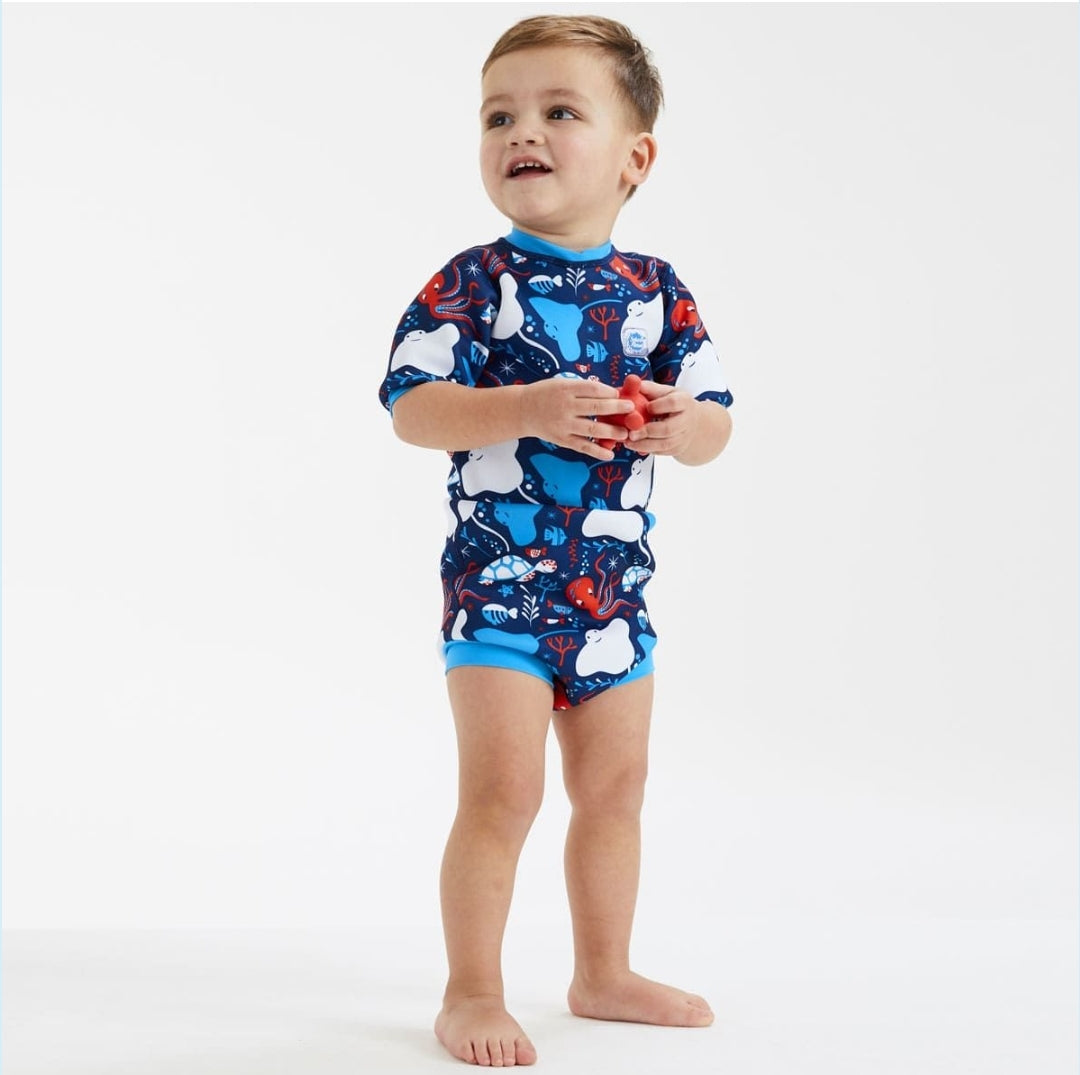 Menino de pé a segurar um brinquedo com fato térmico azul-marinho