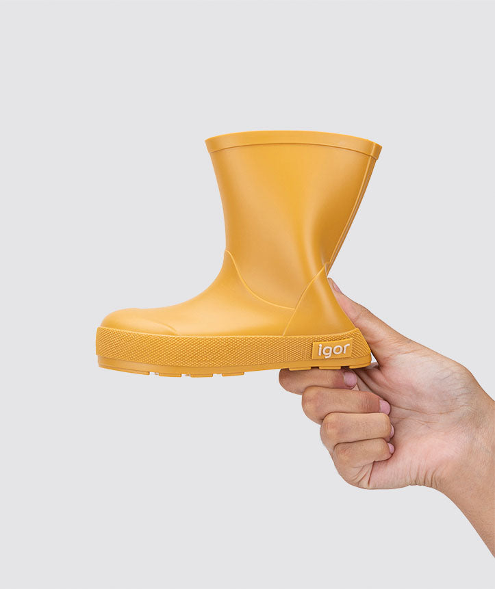 Mão a dobrar a galocha amarelo-mostarda a mostrar a sola flexível